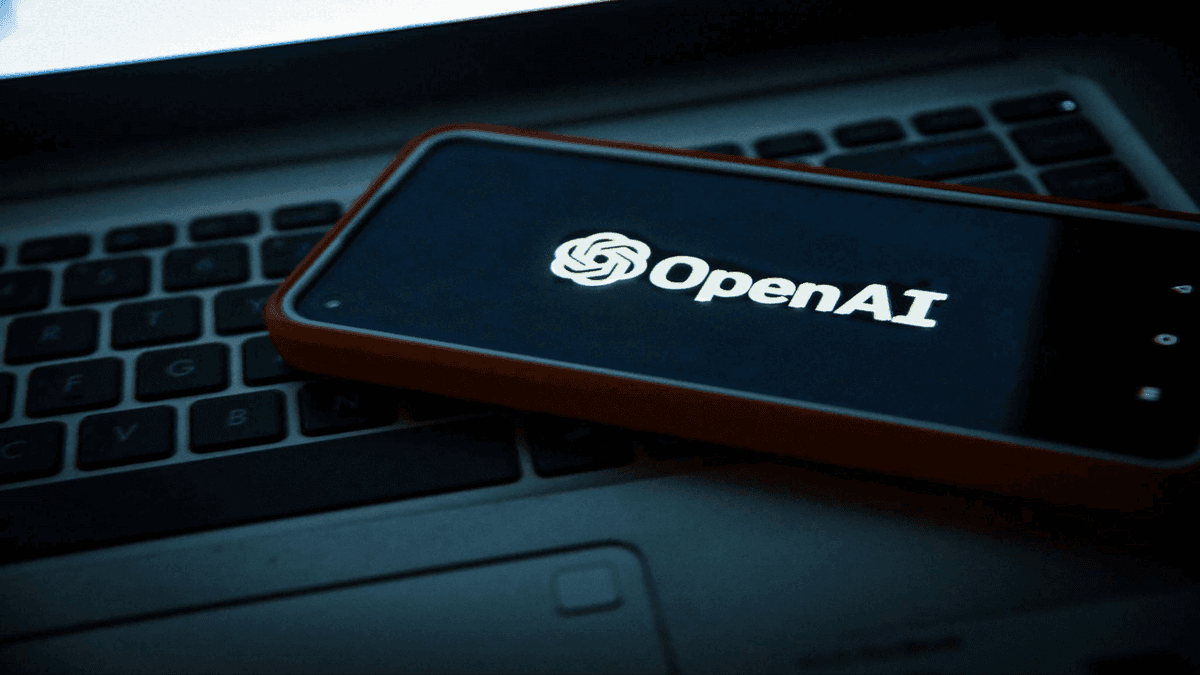 an image of A smartphone with the OpenAI logo on the screen is placed on a computer keyboard