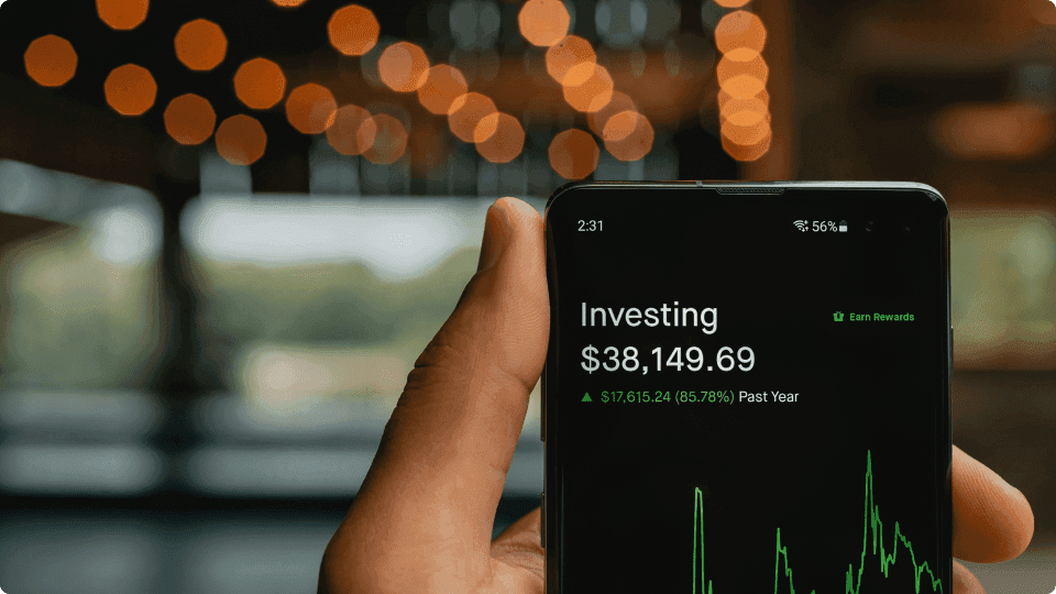 an image of Hand holding a phone displaying the words 'investing'