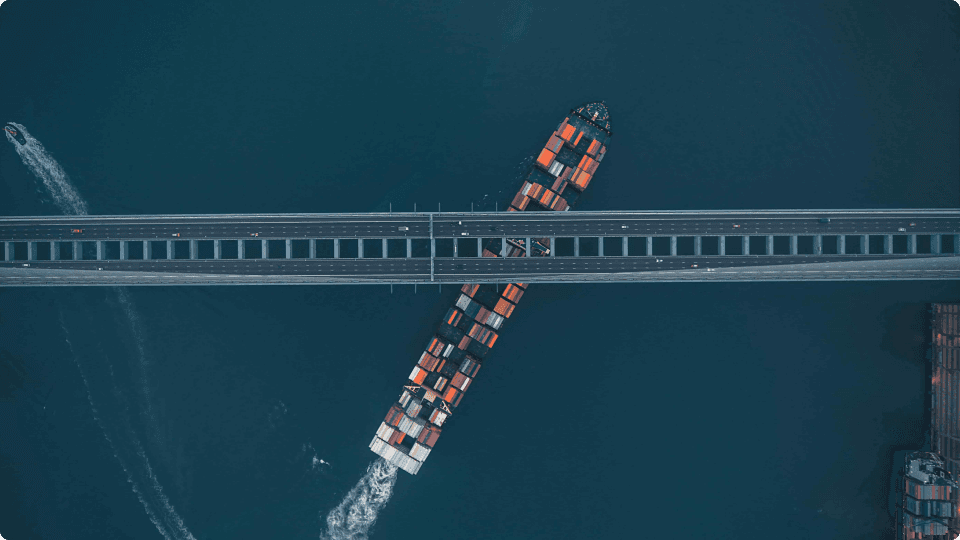 an image of A cargo ship sailing beneath a bridge
