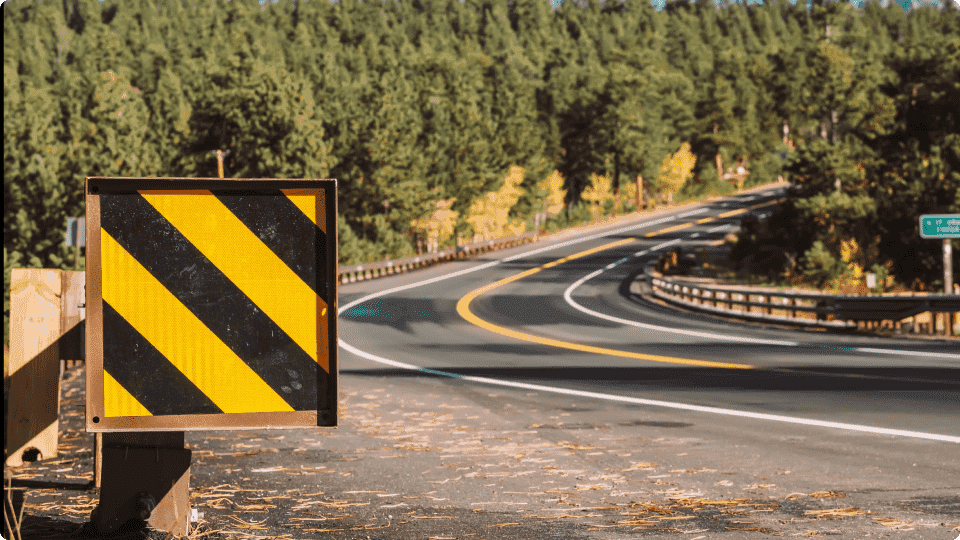an image of Winding road with a caution sign