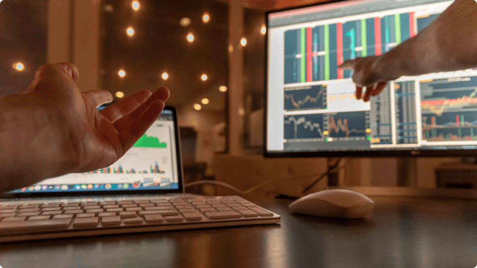 an image of Hands pointing at a stock trading screen